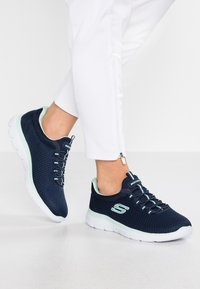 Navy mesh sneakers with light mint accents, round toe, elastic lacing, padded collar, and a white rubber sole featuring a textured pattern.
