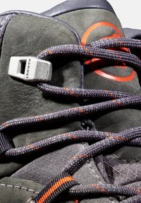 Bottillon de randonnée gris foncé avec une tige en suède, des accents orange, une semelle texturée et un crochet en métal avec le logo "MAMMUT" et des lacets à motif.