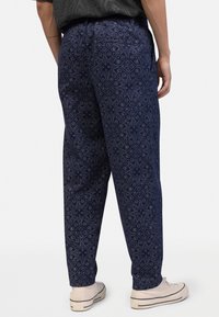 Navy patterned trousers with a floral design, featuring a relaxed fit and elastic waistband. Material is lightweight with a smooth texture.