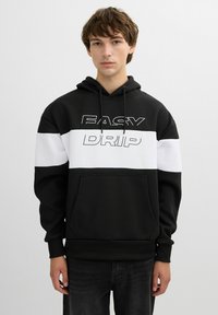 Sudadera en blanco y negro con bolsillo frontal, que presenta un texto en negrita "EASY DRIP" en blanco contrastante en el pecho. Material suave con textura acanalada.