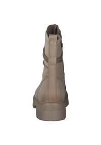 Stivaletto beige con materiale in pelle liscia, lati testurizzati, tacco robusto e dettagli elastici, dotato di zip sul retro per facilitare la calzata.