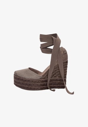 Brązowy koturn espadryli z plecioną podeszwą z juty, materiałowym wierzchem i krzyżującymi się paskami wokół kostki. Zaokrąglony czubek, fakturowane wykończenie.