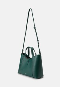 Sac à main en cuir vert avec double anses supérieures et une bandoulière amovible ; présente un design angulaire et un logo discret.