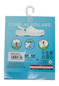 Hvite plastklosser med ventilasjonshull, med en stropp. Emballasjen inneholder bruksanvisning og ikoner for kompatibilitet med Jibbitz-charms.