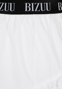 Witte rok met zwarte elastische tailleband met het "BIZUU" logo in wit. Gladde textuur, geplooid design en subtiele randdetails aan de zoom.