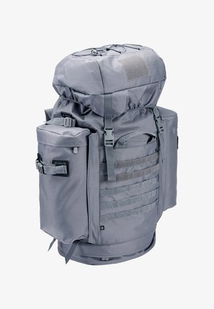 Duży szary plecak taktyczny z wieloma przegrodami, regulowanymi paskami i taśmą MOLLE z przodu i po bokach do mocowania akcesoriów.