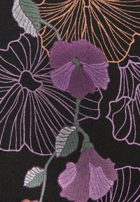 Schwarzer Stoff mit einem floralen Muster, das lila und lavendelfarbene Blumen, grüne Blätter und orangefarbene Umrandungen auf einem strukturierten Hintergrund zeigt.