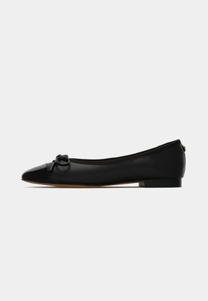 Black flat shoe made of smooth leather, with a rounded toe and a decorative bow detail on the front. Features a low, square heel.