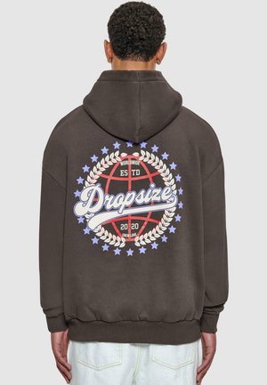 Brauner Kapuzenpullover mit Kapuze, der auf der Rückseite ein großes Grafikdesign zeigt: einen Basketball, umgeben von einem Lorbeerkranz, Text und Sternen.
