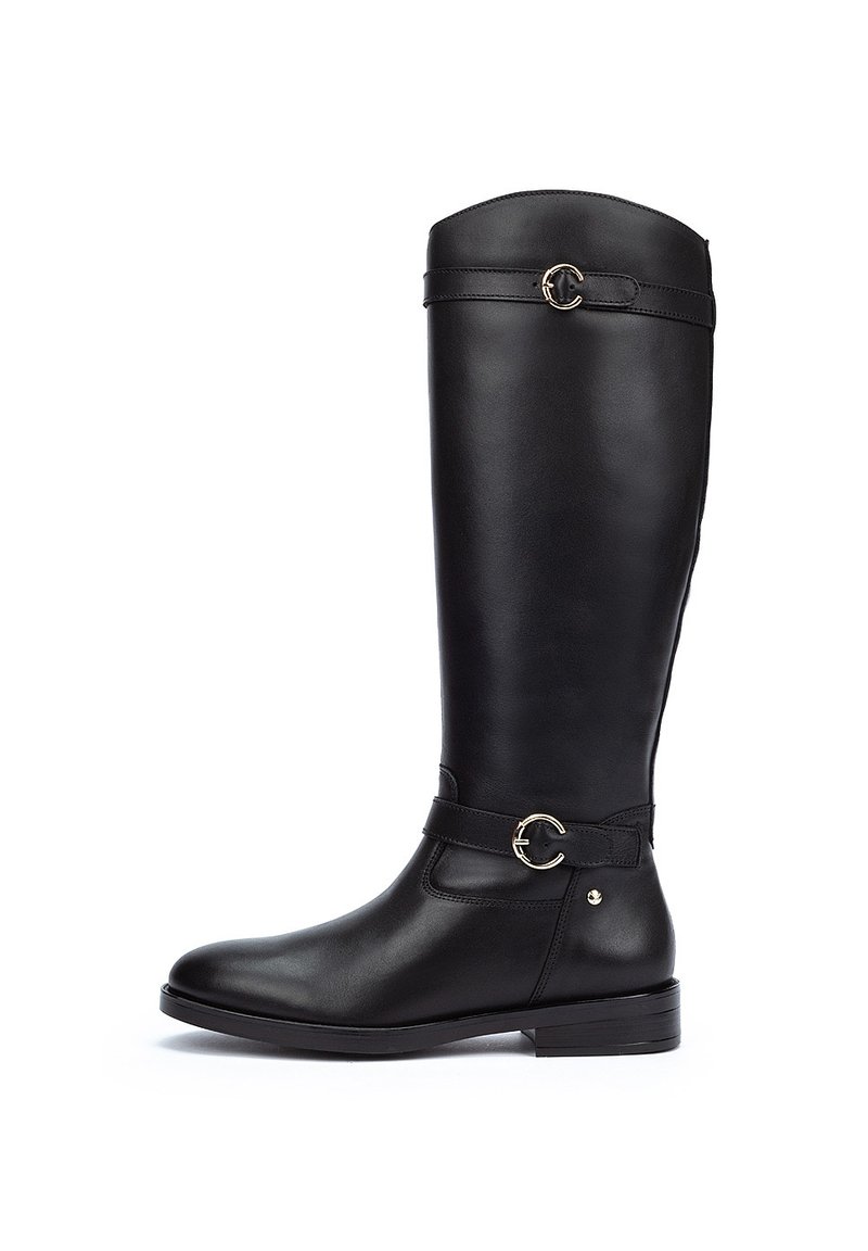 Botas de cuero negras hasta la rodilla con una textura suave, que cuentan con una correa y un acento de herrajes plateados. Suela plana y diseño de punta redondeada.