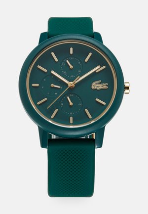 Montre en silicone verte avec un cadran rond, des accents dorés, trois sous-dials et des marqueurs d'heure en relief. Bracelet texturé pour une meilleure prise et un confort optimal.