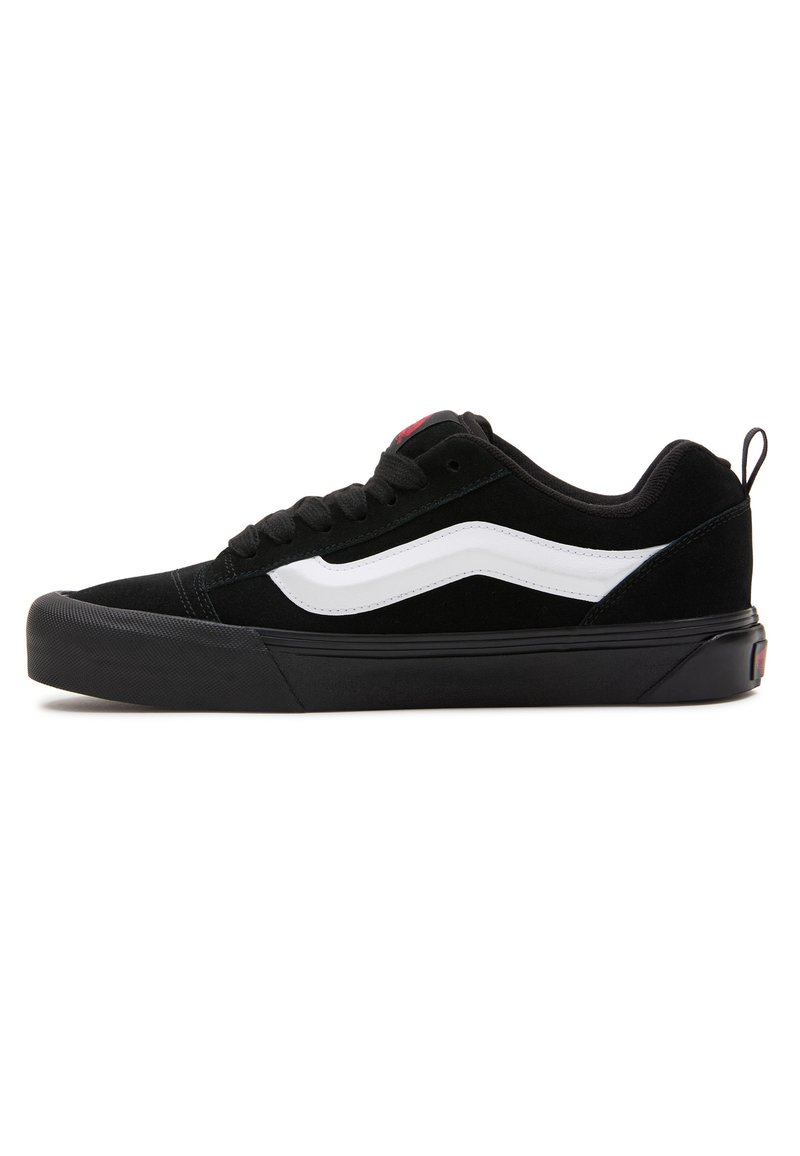 Sneaker in suede nero con dettagli bianchi, suola in gomma e chiusura con lacci. Presenta un colletto imbottito e un piccolo tab sul tallone per facilitare la calzata.
