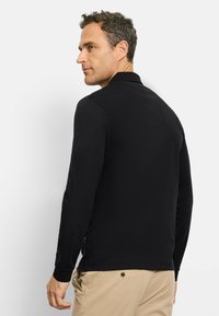 Zwart polo-shirt met lange mouwen, een polokraag en manchetten. Gladde textuur, getailleerd ontwerp, met een lichte zijsplit.