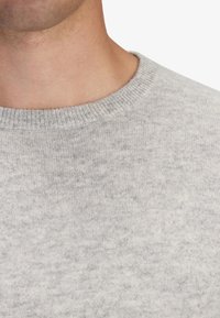 Ljusgrå tröja med ribbad rund halsringning och mjukt, texturerat tyg. Ytan visar ett subtilt, melerat mönster.