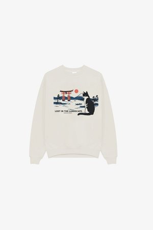 Hvit genser med grafikk av en svart-hvitt katt som ser på en rød torii-port, fjell, rød sol og teksten "Lost in the landscape".