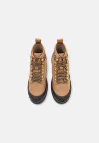 Stivali alla caviglia in pelle color cuoio con punta arrotondata, suola in gomma nera, dettagli dorati e lacci decorati. Dotati di una linguetta posteriore per facilitare la calzata.