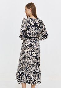 Sukienka z długim rękawem w kolorze granatowym z beżowym kwiatowym wzorem, z dopasowaną talią, rozkloszowanym dołem i falbaniastym wykończeniem. Miękka tkanina o gładkiej strukturze.