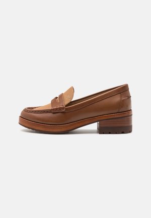 Mocassin en cuir marron avec languette en tissu beige, détails cousus et talon en bois épais sur fond blanc.