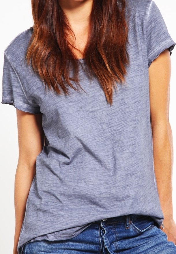 T-shirt gris à manches courtes avec une coupe décontractée, présentant une texture subtile et un tissu doux. Manches retroussées remarquables et ourlet légèrement arrondi.