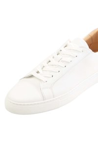 Sneaker in pelle bianca con punta arrotondata, lacci piatti e dettagli cuciti. Suola in gomma con leggero texture, branding minimal sul lato.