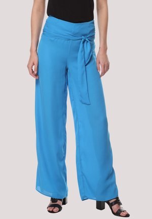 Pantalones de pierna ancha en azul brillante, con una cinturilla atada, textura suave y diseño fluido, combinados con sandalias de tacón negras.