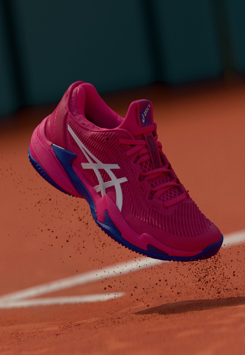 Asics tenisa apavu iezīme ir spilgti rozā acs augšdaļa, balts logo, zili akcenti un teksturēta zole ar dinamisku formu.
