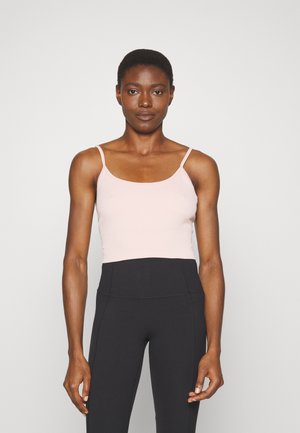 Top de alças finas, em rosa claro, com textura em cordas, combinado com leggings pretas de cintura alta, com design sem emendas e textura suave.