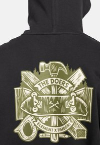 Hoodie noir avec un grand graphisme détaillé. Le design met en avant des outils, du bois et un skateboard, avec "LES FAISANTS" en caractères gras.