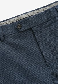 Marine gemusterte Hose aus strukturiertem Stoff mit einem Knopfverschluss, versehen mit einem grauen Taillenfutter und sauberen Nähdetails.