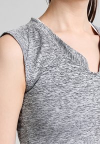 Top gris jaspeado de manga corta con diseño de escote en V. Textura suave, ligera elasticidad y costura visible en el escote.