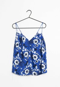 Blue floral camisole with thin spaghetti straps, featuring white and black flowers and green leaves on a smooth fabric background.