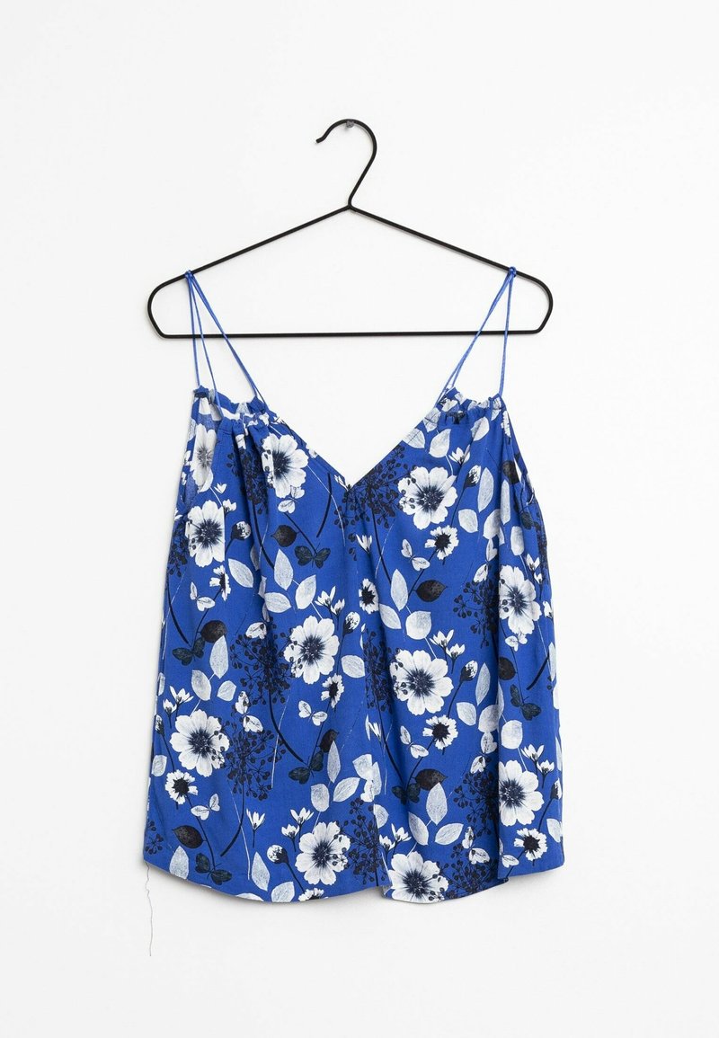 Blue floral camisole with thin spaghetti straps, featuring white and black flowers and green leaves on a smooth fabric background.