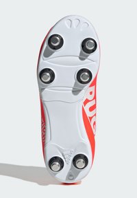 Puntti punainen jalkapallokengän pohja, jossa on viisi mustaa metallista nappulaa. Valkoinen kuvioitu ulkopohja, jossa on "adidas"-logo ja kuvioitua sisustusta sivuilla.