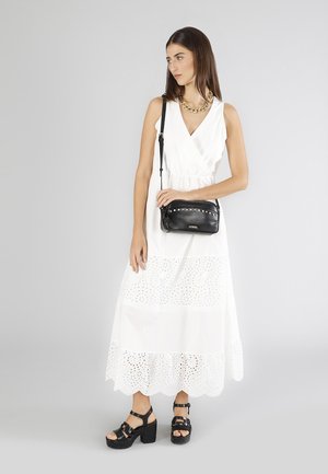 Hvid maxi kjole med øjenlågsmønstre, v-udskæring og lagdelt design parret med en lille sort crossbody taske og chunky sorte platform sandaler.