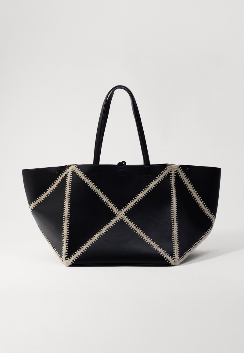 Black leather tote bag with geometric design, accented by beige stitching. Features two sturdy handles and a spacious interior.