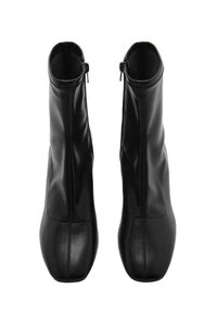 Bottines noires en cuir lisse, avec un design épuré, un bout pointu et une fermeture éclair sur le côté pour un enfilage facile.