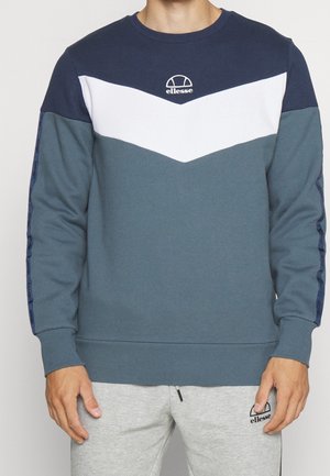 Sudadera de cuello redondo en azul marino, blanco y verde azulado. Patrón de chevron con puños y dobladillo acanalados. Logotipo centrado en el pecho y acentos del logotipo en las mangas.