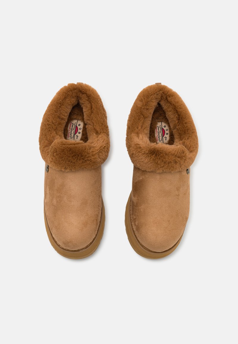 Pantofole slip-on in suede beige con un colletto in morbido pelliccia sintetica beige, interno imbottito e suola in gomma testurizzata. Design semplice e arrotondato.