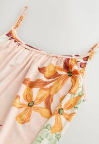 Top fără mâneci roz deschis, cu modele florale vibrante în nuanțe de portocaliu și verde. Material moale, cu adunături ușoare la nivelul decolteului.