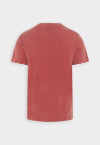 T-shirt in cotone rosso con scollo rotondo, maniche corte e una texture morbida e leggermente sbiadita. Dettagli delle cuciture alle maniche e all'orlo.