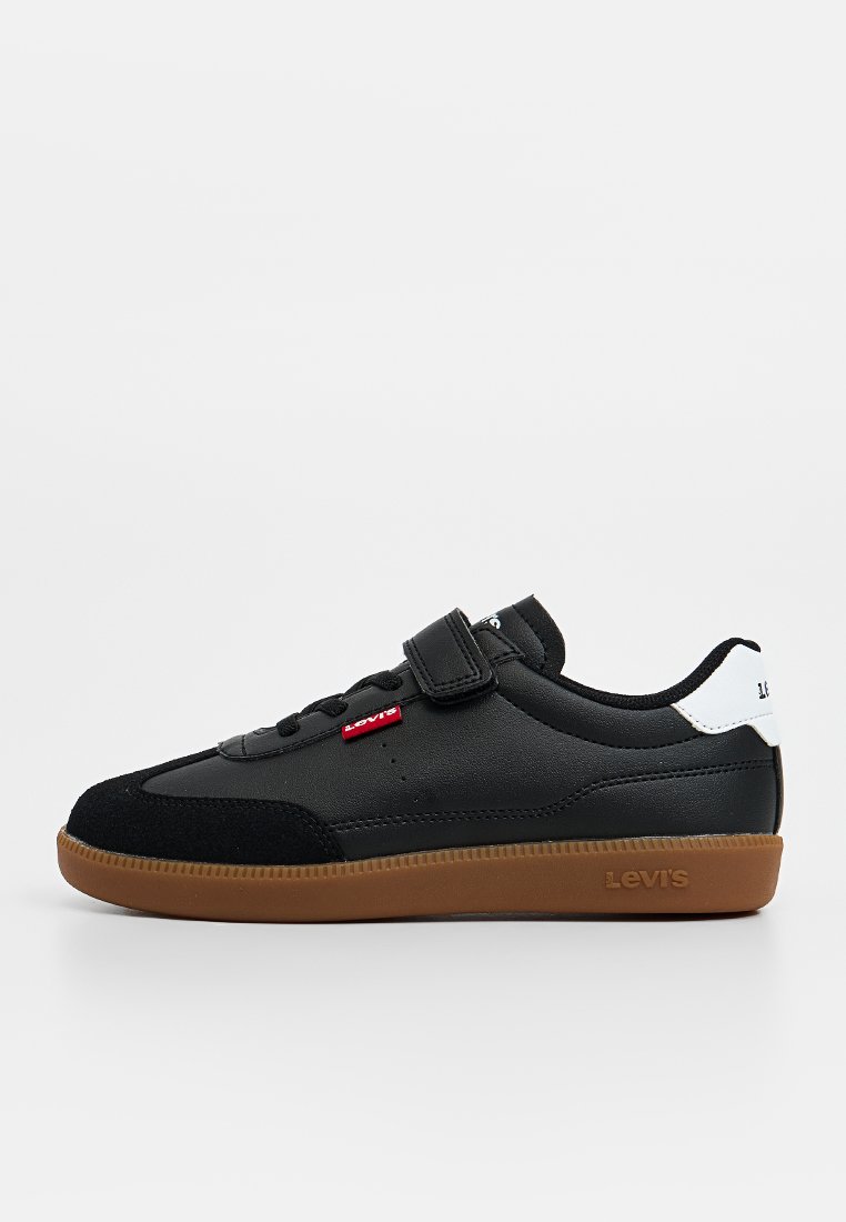 Zwarte sneaker van leer en suède, met een gumrubberen buitenzool, veter- en klittenbandsluiting, en een witte accenten op de hiel met een logo.