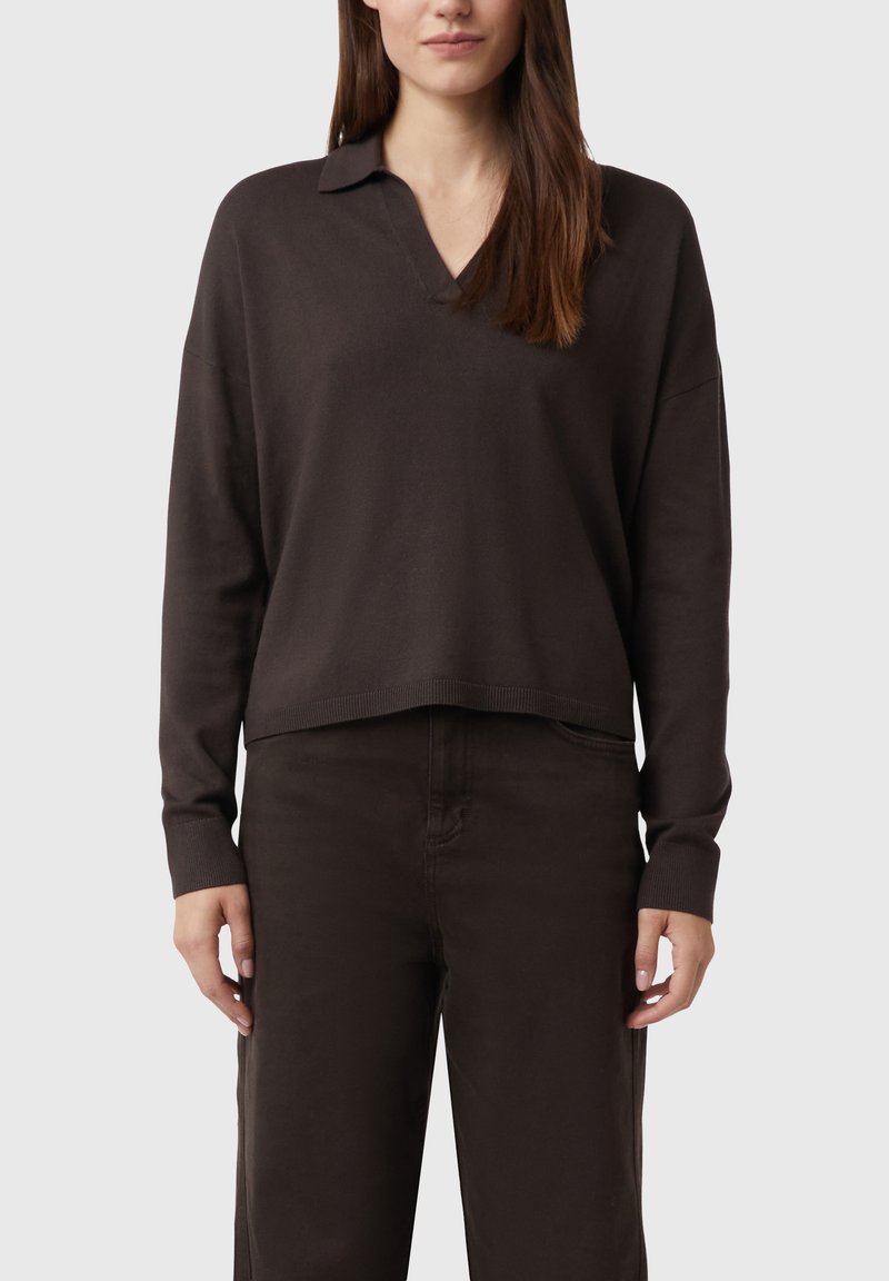 Ciemnobrązowy sweter z dekoltem w kształcie litery V i kołnierzykiem, luźny krój, długie rękawy i ściągacze na mankietach. W zestawie z pasującymi ciemnymi spodniami.