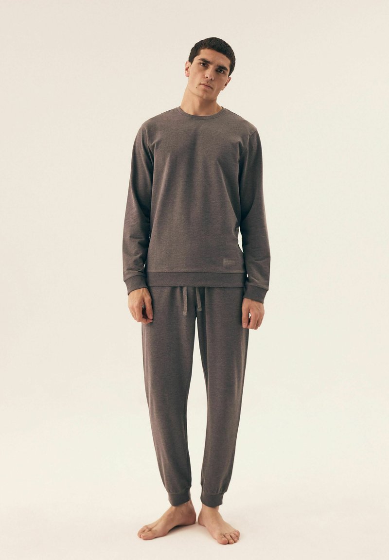 Szary zestaw bluzy i spodni w pasującym kolorze, wykonany z miękkiego materiału, z długimi rękawami, elastycznymi mankietami i sznurkiem w talii. Prosty design, minimalne detale.