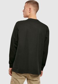 Tricou negru cu mânecă lungă din bumbac, cu guler rotund și o croială lejeră, având o textură netedă și un design minimalist.