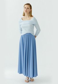 Blauwe maxi rok met geplooide tailleband, gecombineerd met een fitted top in wit en lichtblauw gestreept. Glad stof, lange mouwen, off-shoulder ontwerp.