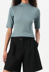 Prążkowany top z wysokim, przylegającym kołnierzem i krótkimi rękawami, zestawiony z czarnymi, dopasowanymi szortami z paskiem, tworzącymi dopasowaną sylwetkę.