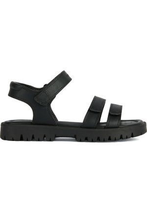 Sandalias de cuero negro con dos correas ajustables de Velcro, una plantilla contorneada y una suela de goma resistente con un diseño de relieve profundo.