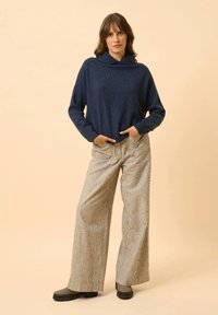 Námořnická pletená mikina s límcem, spolu s širokými pruhovanými kalhotami v béžové a šedé barvě. Má uvolněný střih a přední kapsy.