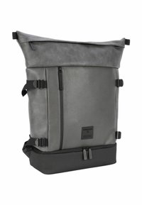 Mochila gris con tapa enrollable, hecha de un material texturizado con una sección inferior lisa. Cuenta con correas laterales ajustables y un bolsillo frontal con cremallera.