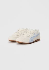 Sneaker in suede beige con accenti azzurri, pannello laterale testurizzato, suola piatta beige e design con lacci con dettagli del logo.